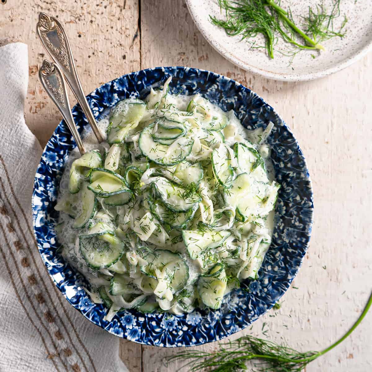 creamy fennel and cucumber salad in a blue and white bowl on a distressed white background