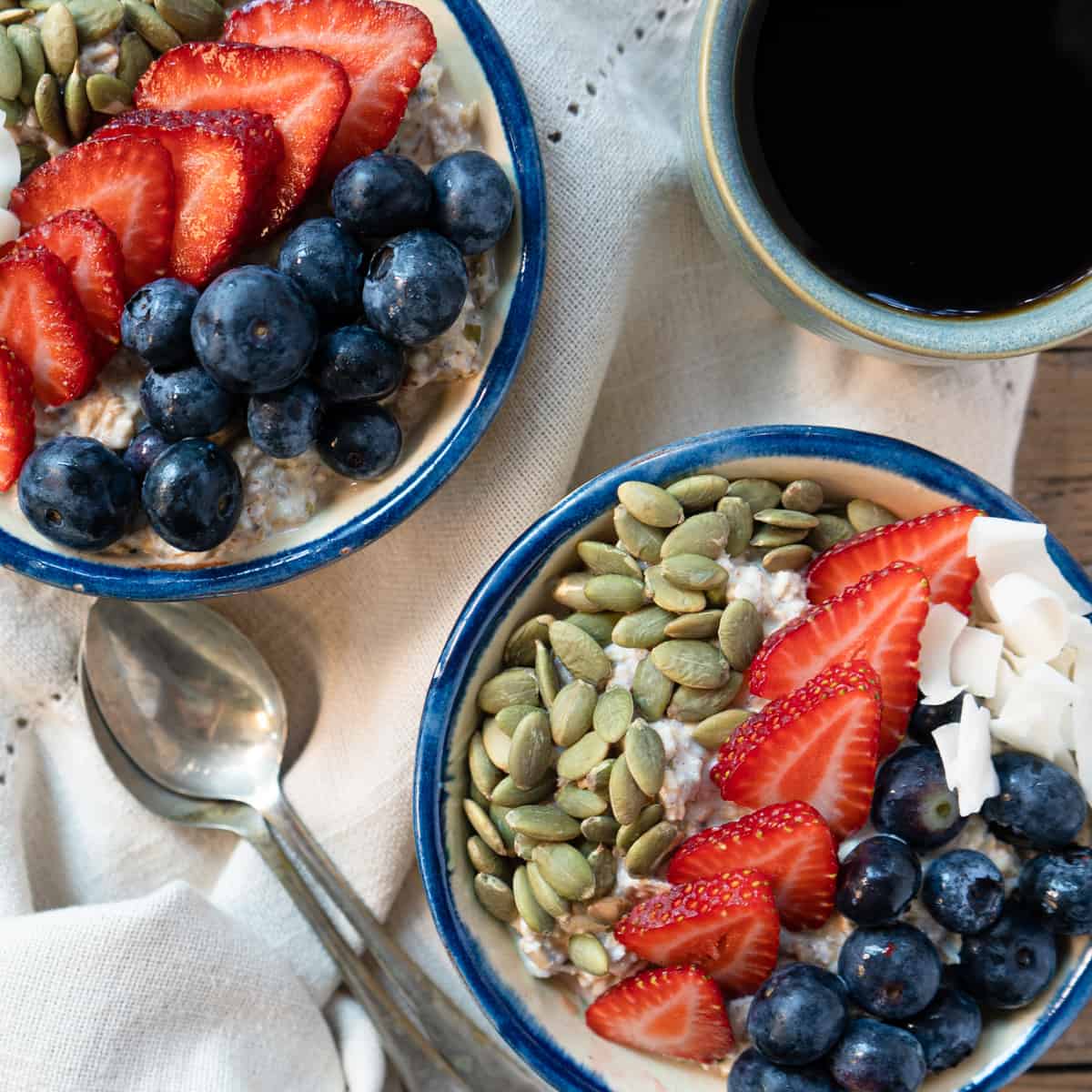 2 bowls of oats with spoons and a cup of black coffee on the side. 