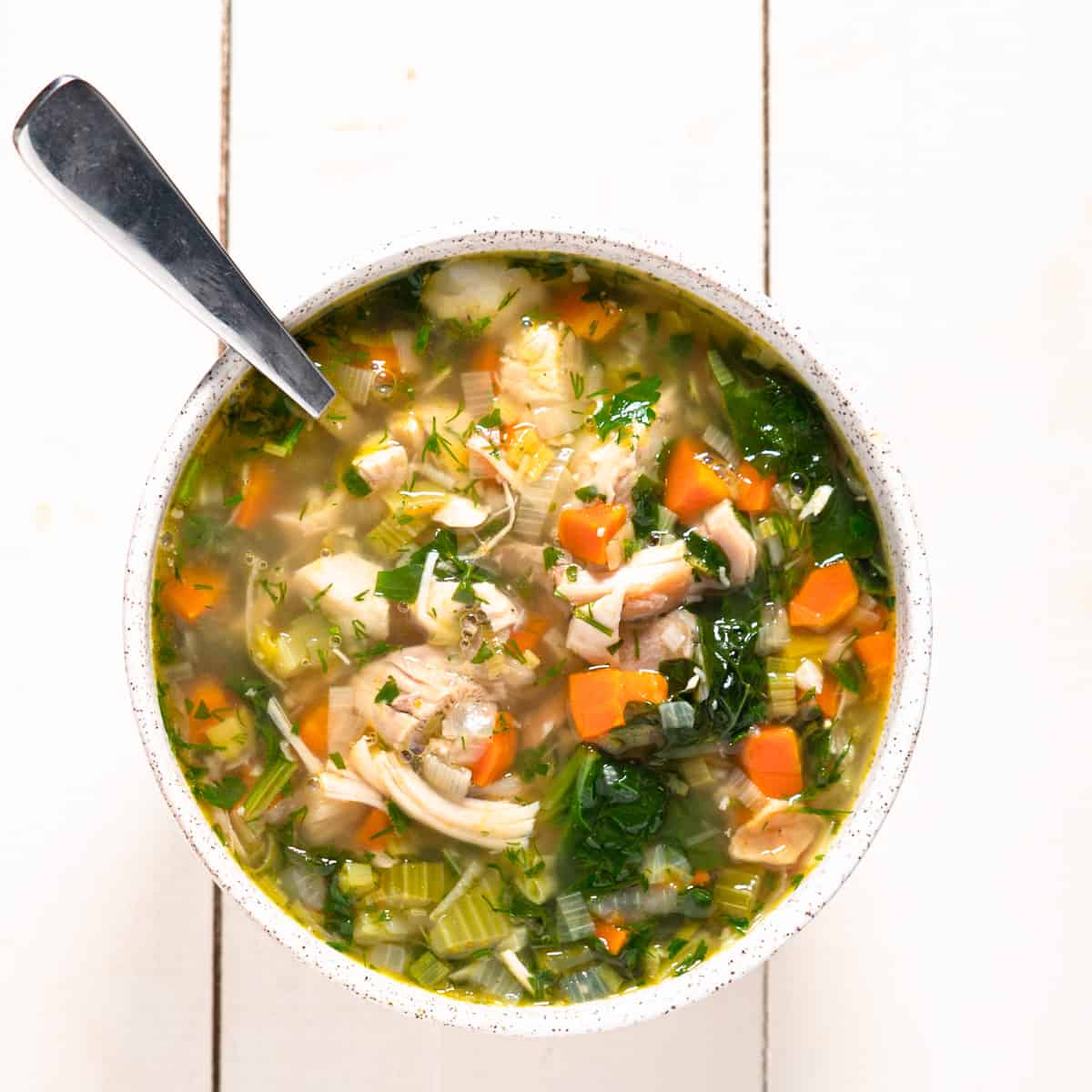 Single bowl of turkey vegetable soup with a spoon.