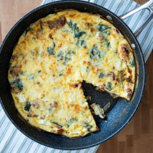 BLT frittata in a black pan on a striped towel