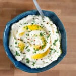 cauliflower and celery root puree in a blue bowl on wood board