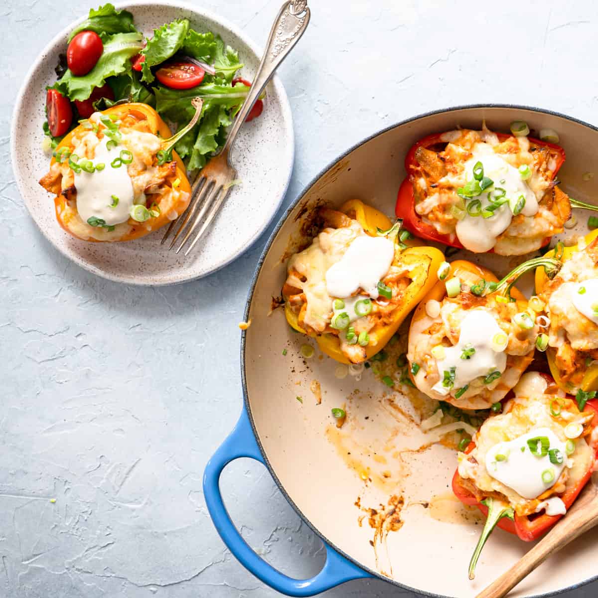 Buffalo chicken stuffed peppers in a baking dish with one serving on the side