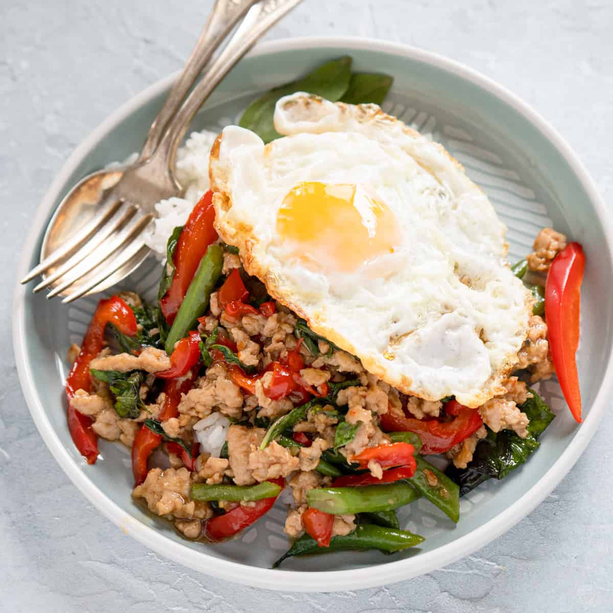 one serving of thai basil chicken topped with a soft yolk fried egg