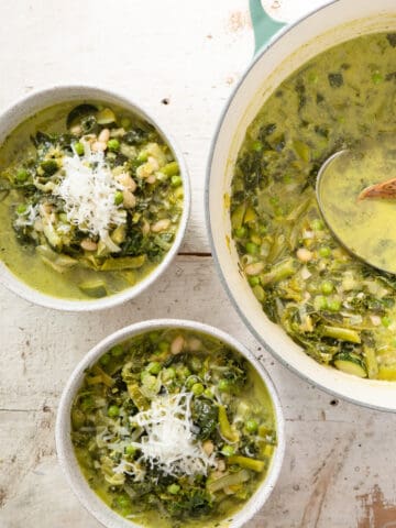 green minestrone soup in serving bowls with the soup pot.