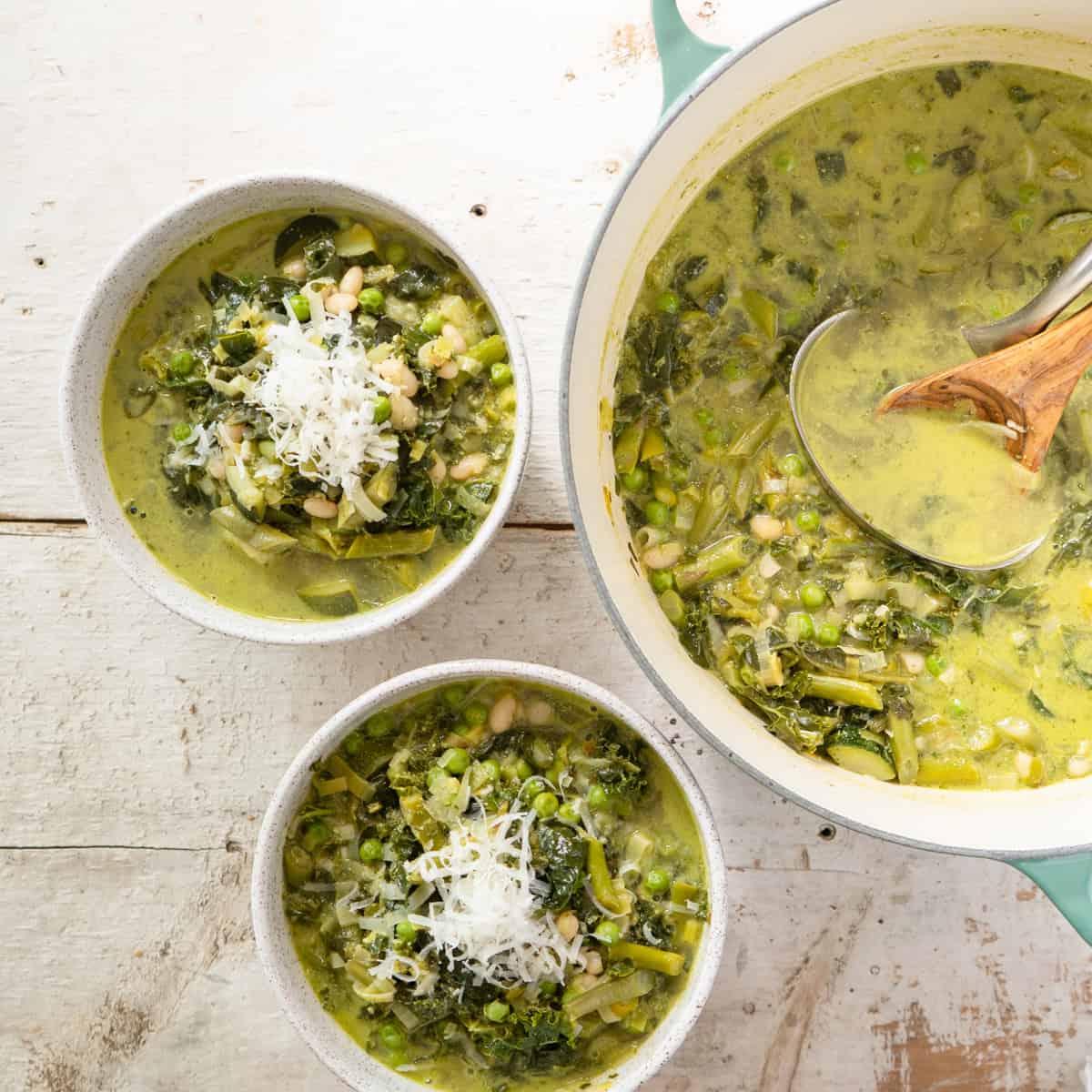 green minestrone soup in serving bowls with the soup pot