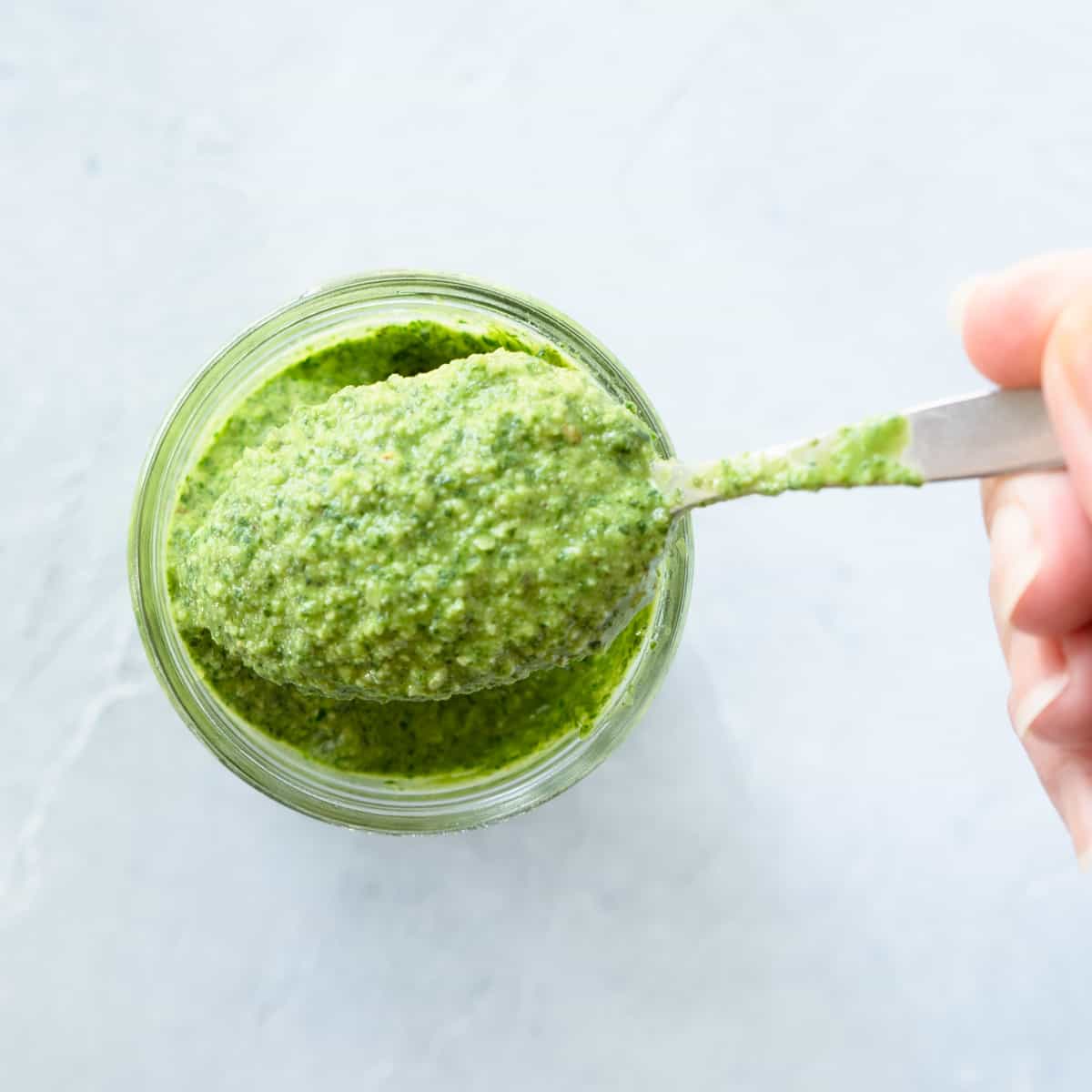 Prepared pesto in a jar showing a spoonful.