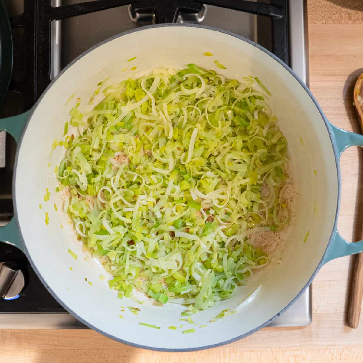 Leeks being fried in a Dutch oven.