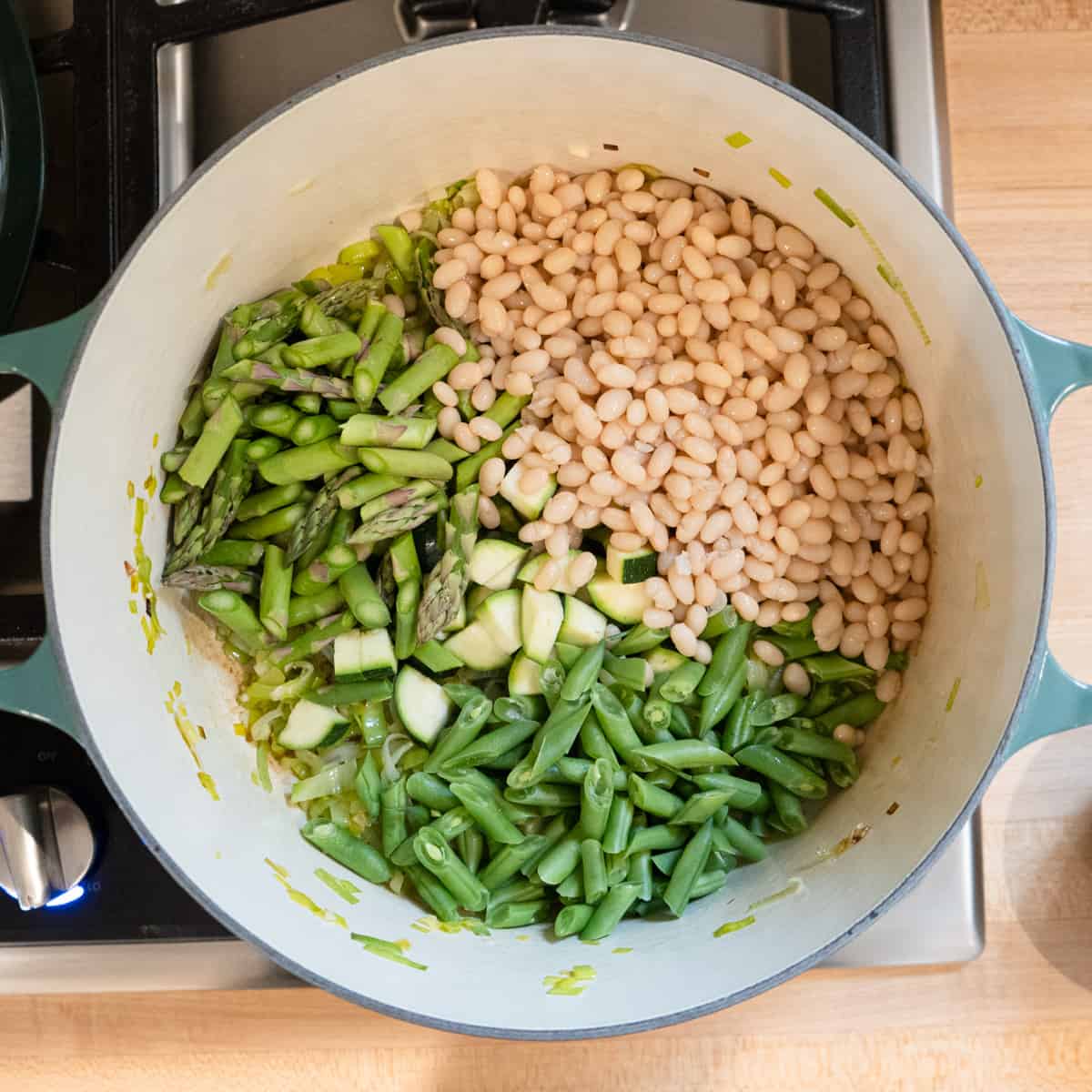 Step 2. Vegetables and beans are being added to the pot.