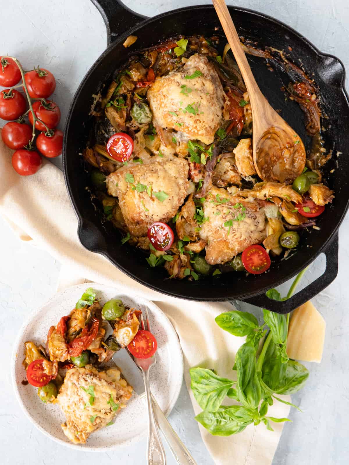 finished chicken and artichokes in cast iron pan with one serving on the side.