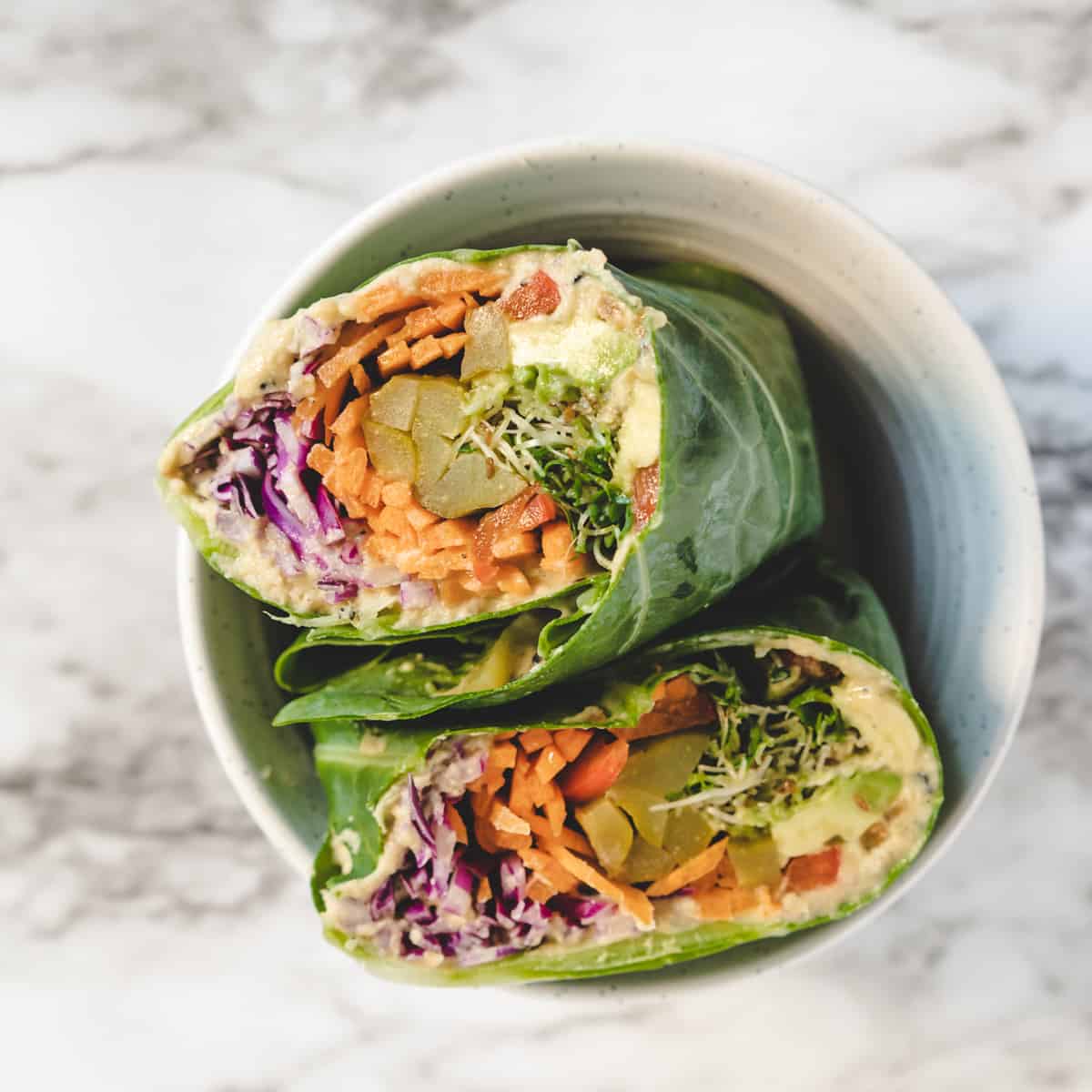 2 collard green wrap halves sitting in a bowl with cut side up. 