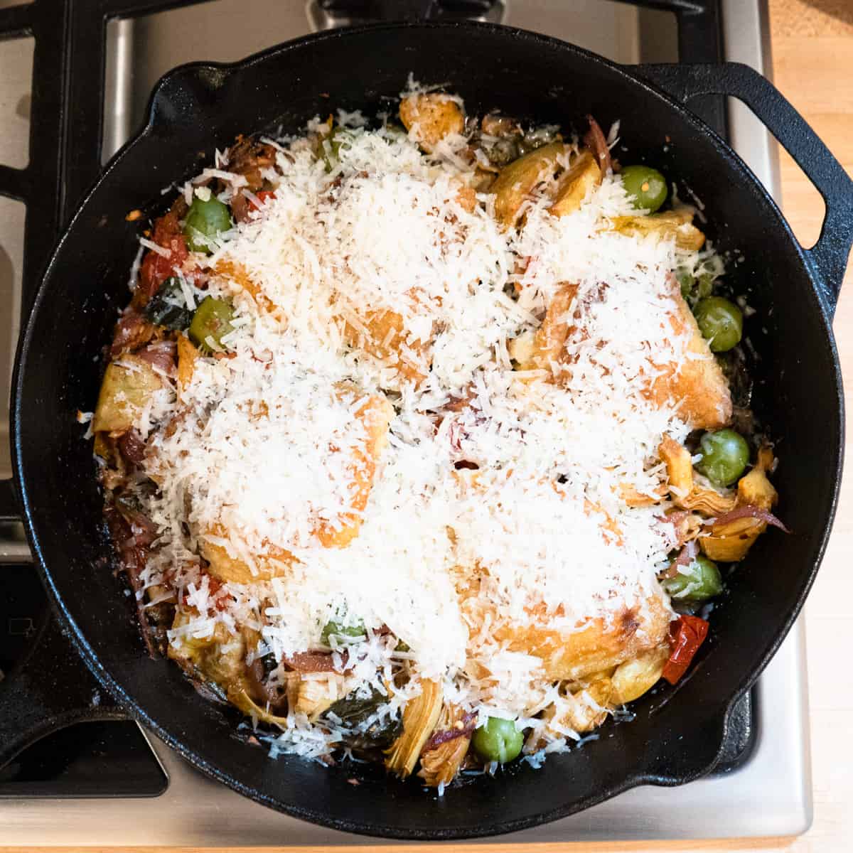 chicken and vegetables in a skillet with parmesan cheese sprinkled on top.