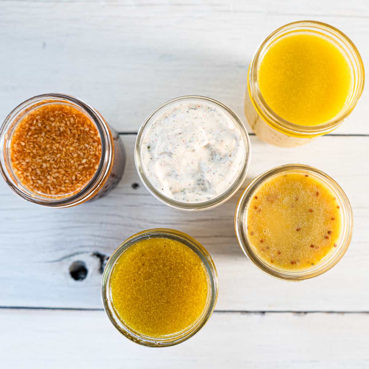 5 salad dressings in mason jars shot from above.