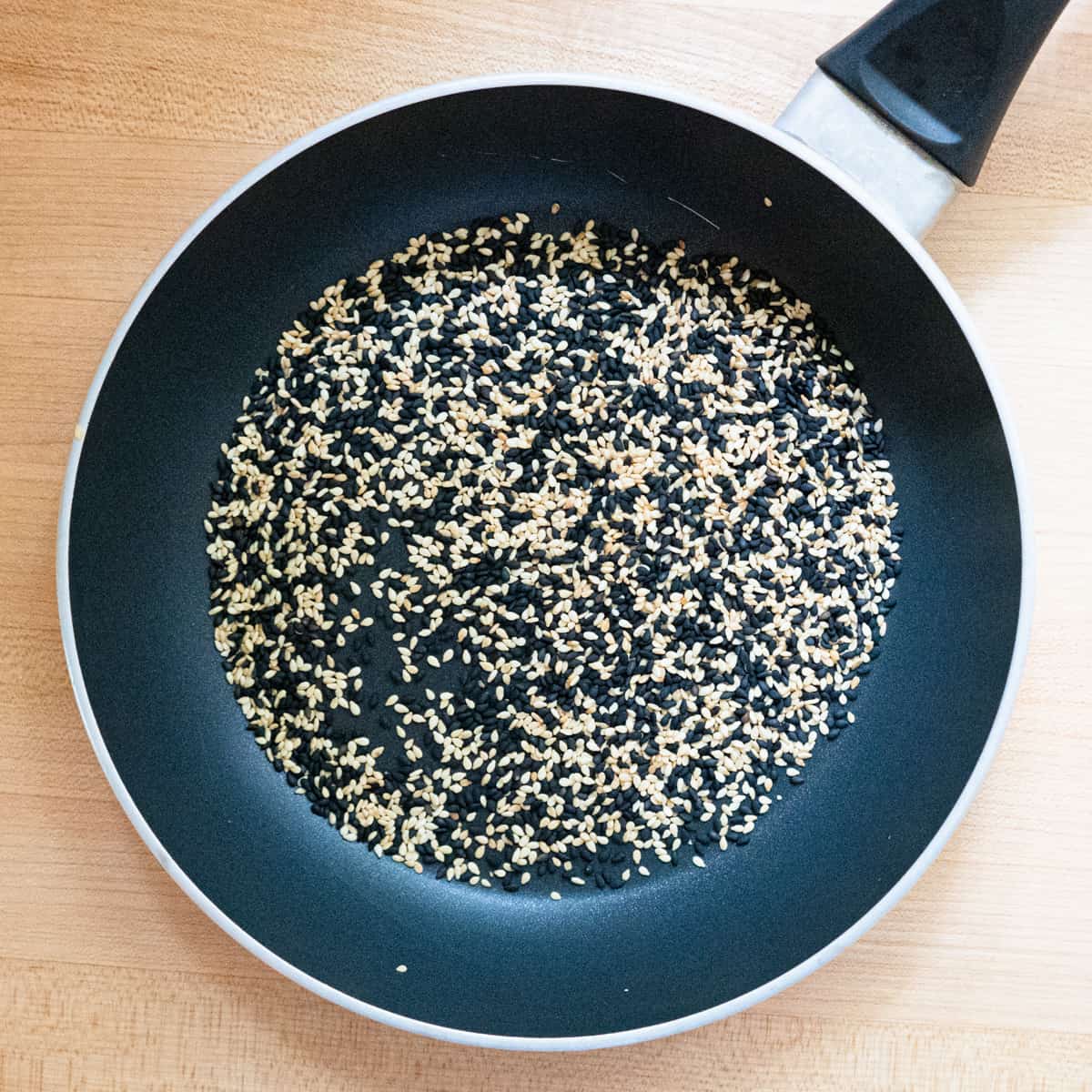 Black and white sesame seeds in a small frying pan after toasting.