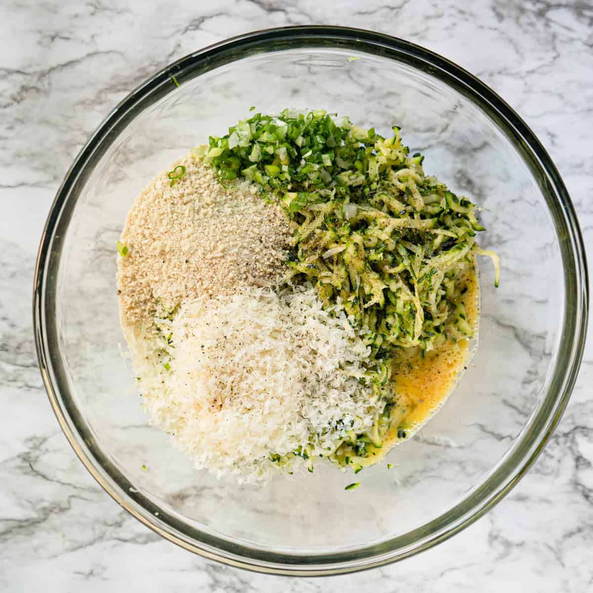 All ingredients for fritter batter in a glass bowl.