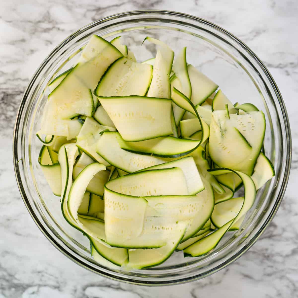 shaved zucchini ribbons in a glass bowl