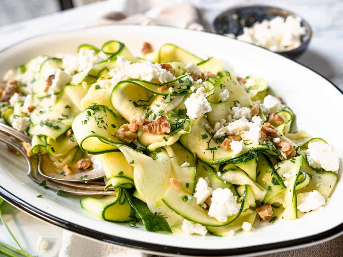 finished salad garnished with fresh herbs, walnuts, and feta cheese.