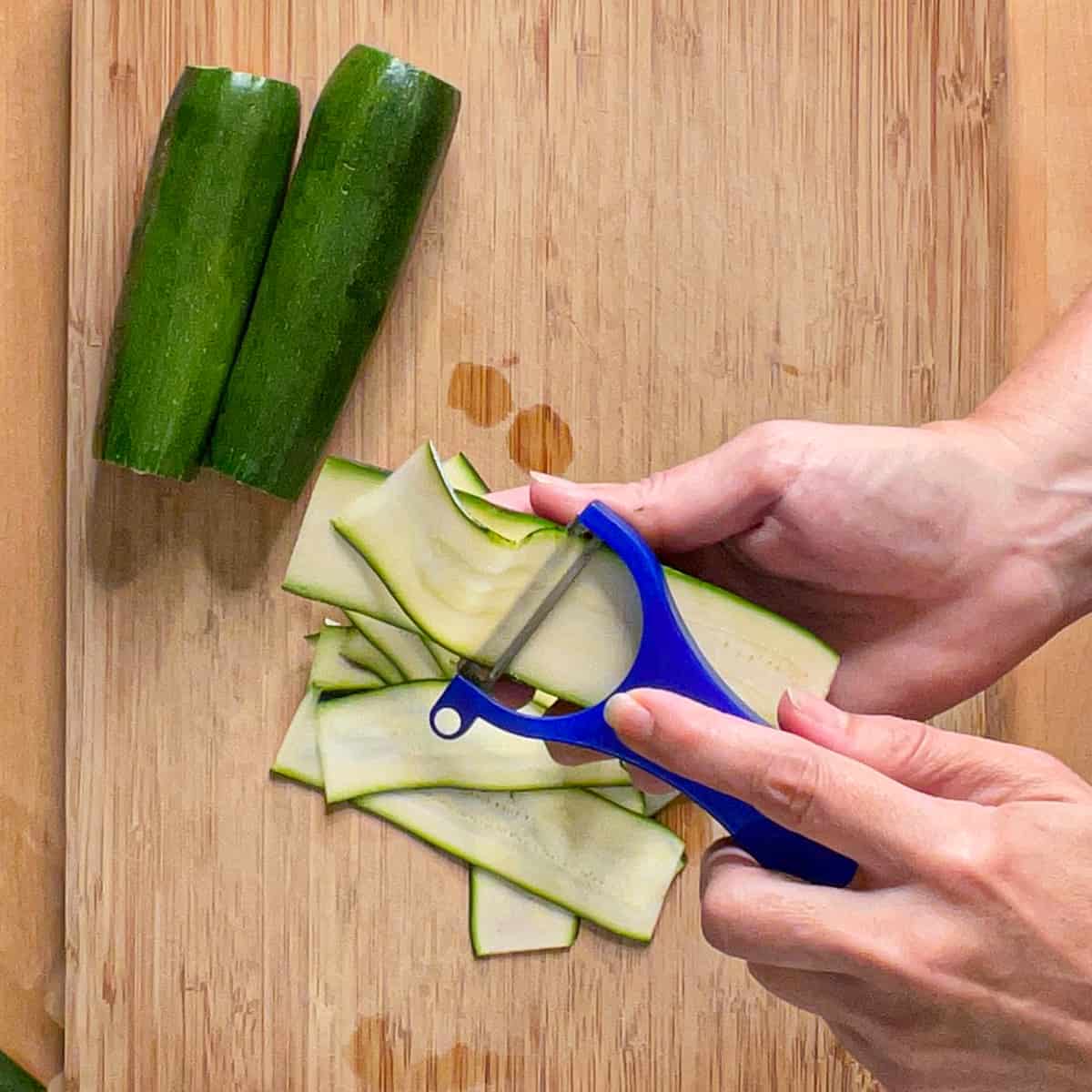 shaving the zucchini with a vegetable peeler.