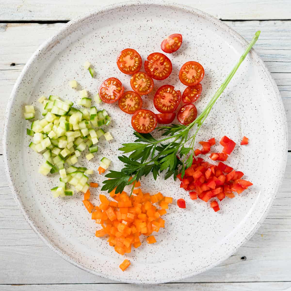 finely diced cucumber and pepper with halved cherry tomatoes and parsley for garnishing soup.