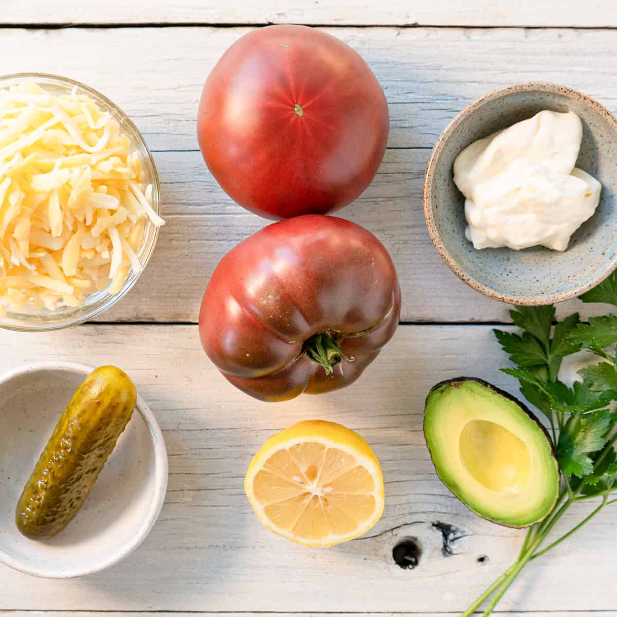 ingredients for tomato tuna melts laid out on a white wood background.