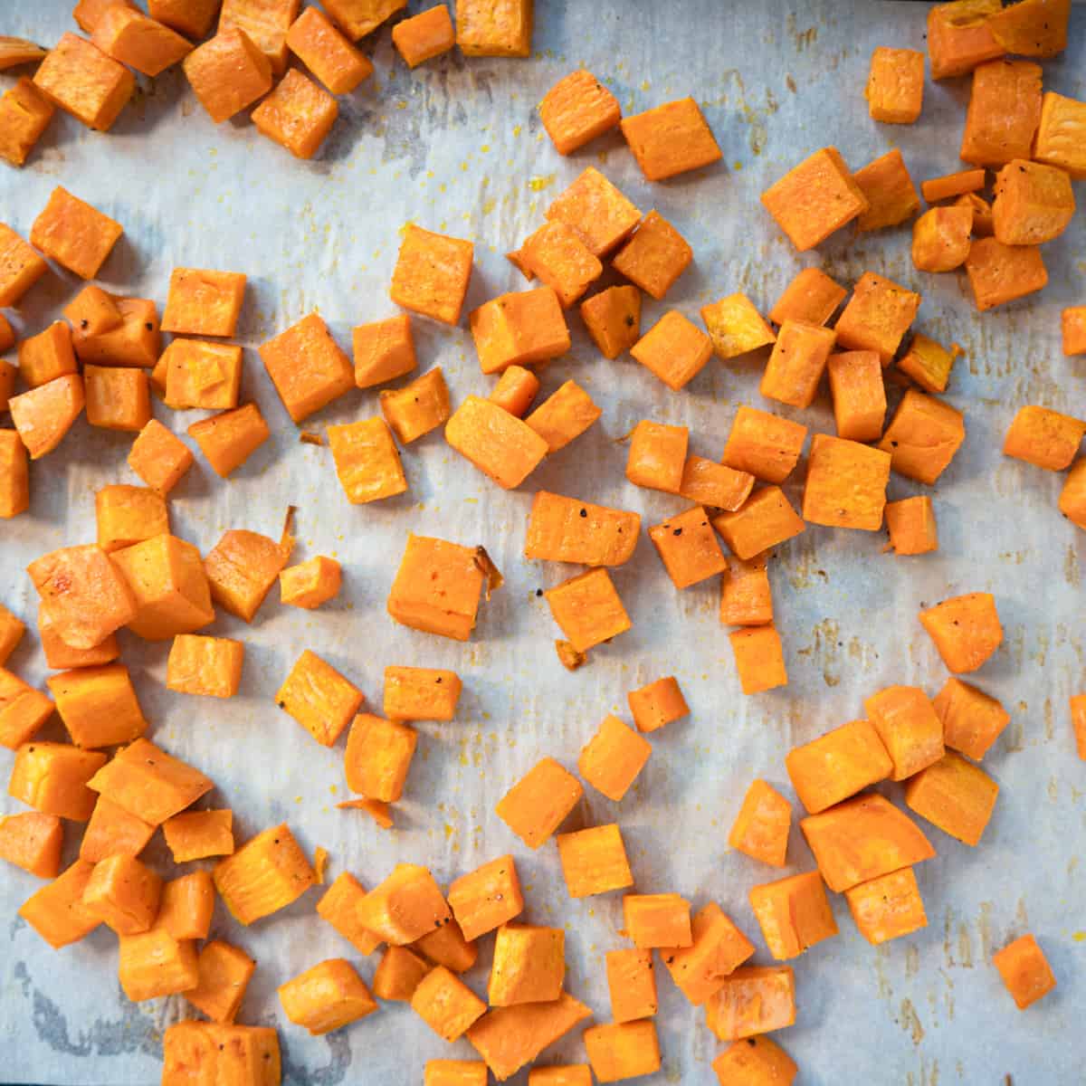cubed sweet potato on a parchment lined baking tray.