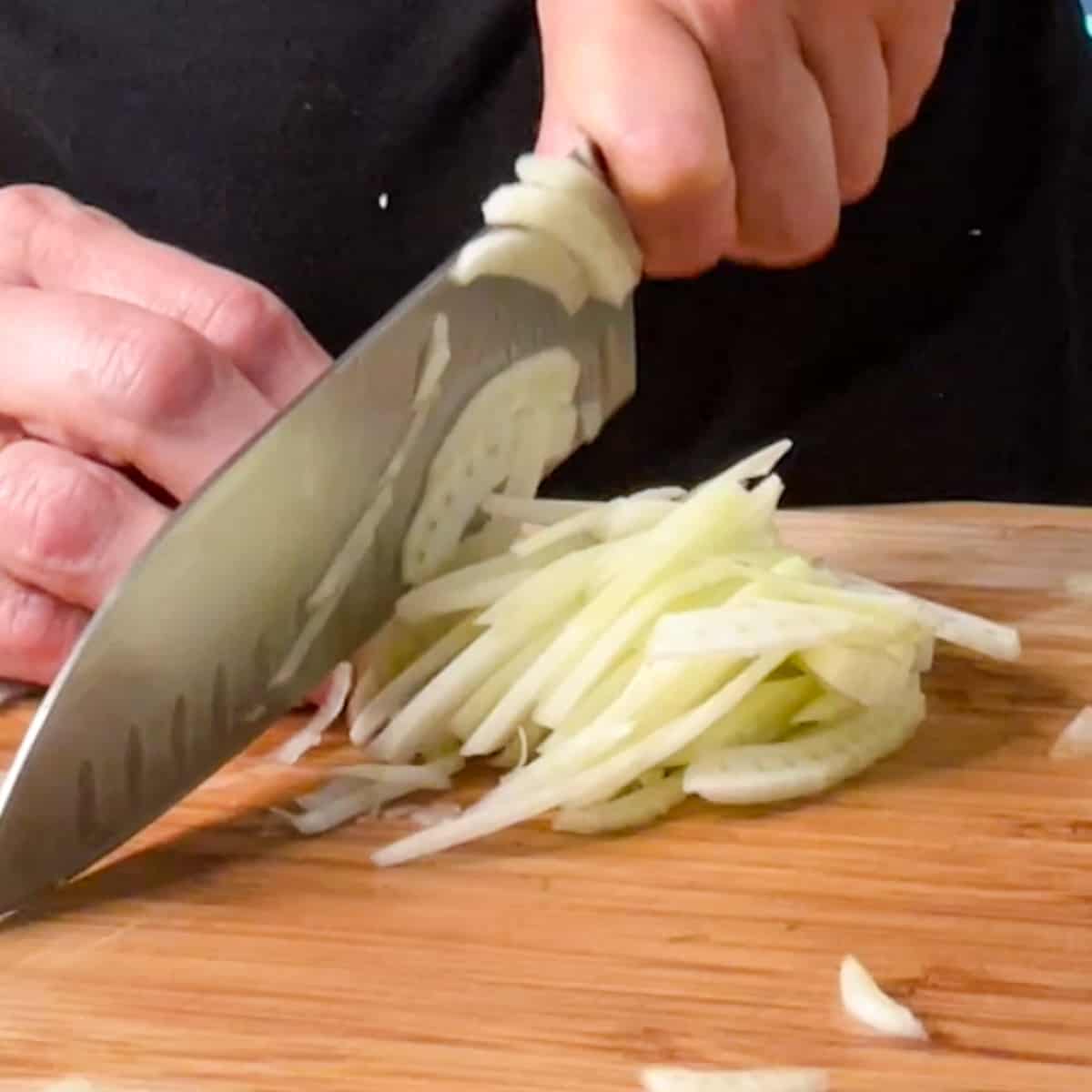 slicing fresh fennel bulb with a chef's knife.