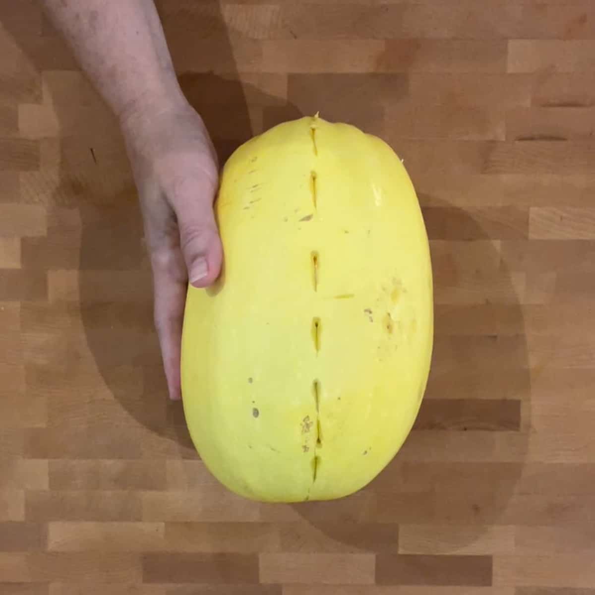 whole spaghetti squash with small cuts lengthwise like a dotted line.