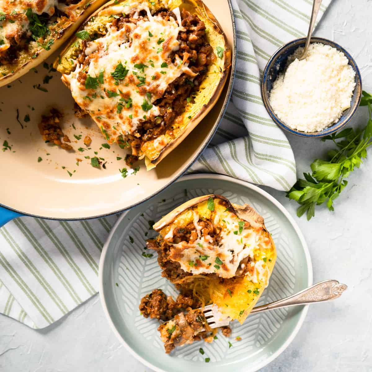 spaghetti squash in a baking dish with one portion on a side plate with a fork.