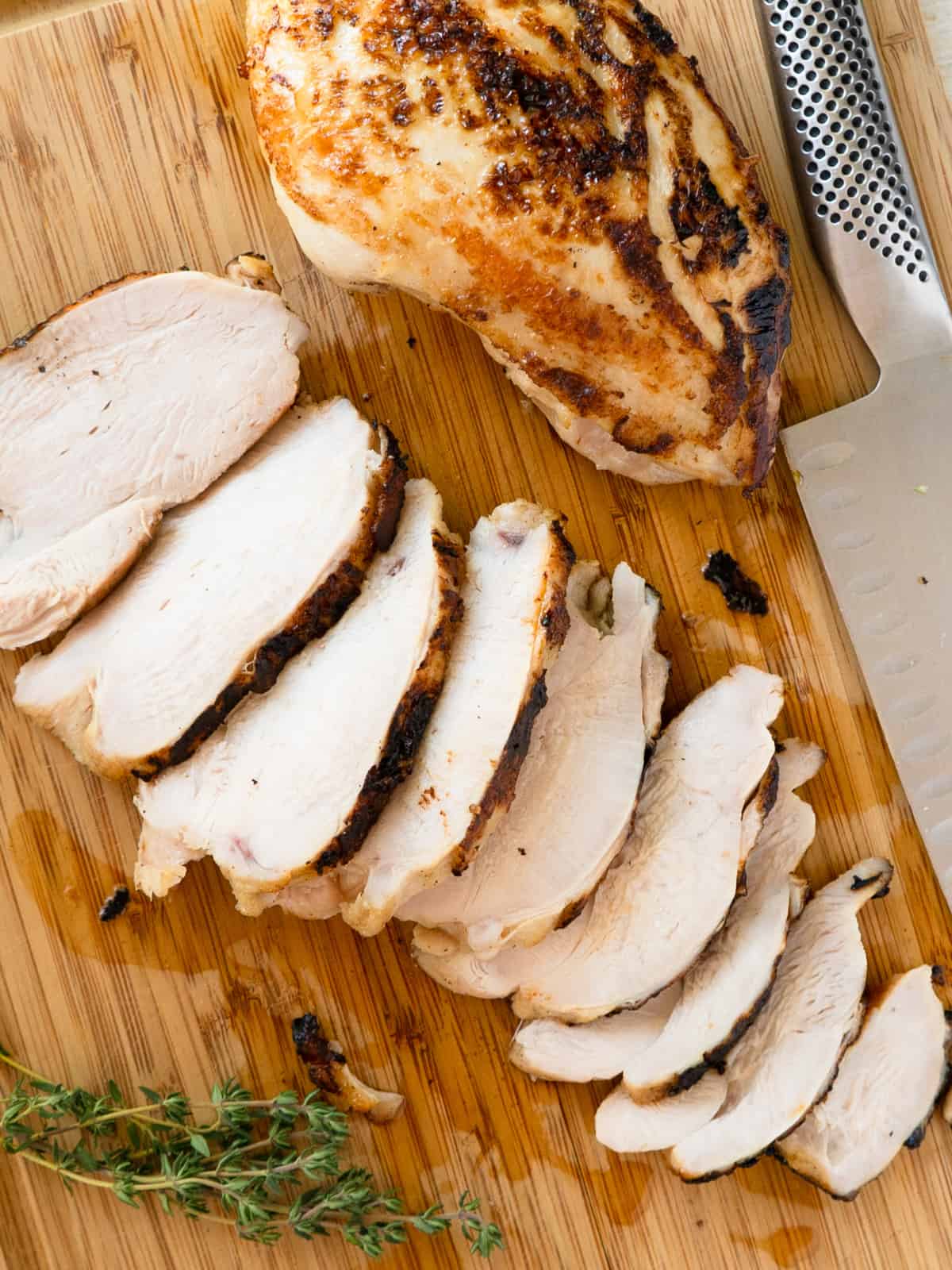 one sliced and one whole cooked turkey breast on a wood cutting board.