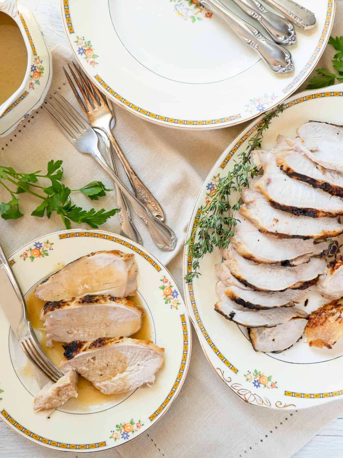 sliced turkey on a china platter with one serving of 3 slices on the side topped with gravy.