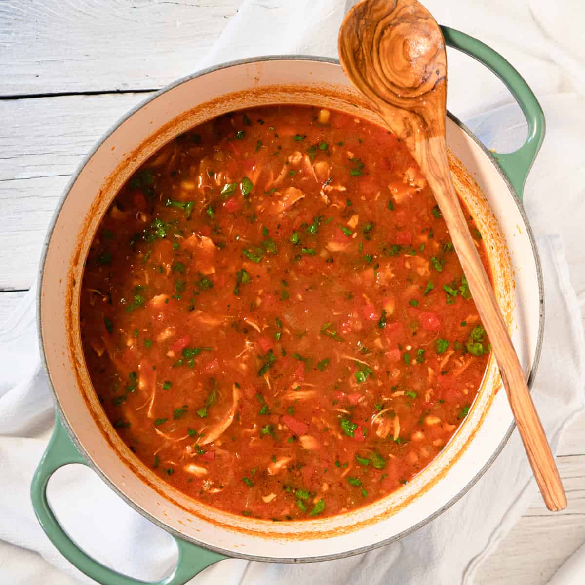 finished soup in large green pot with serving spoon on the side. 