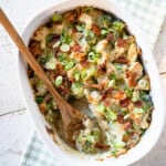 finished casserole in a white baking dish with one serving removed and a wooden spoon.