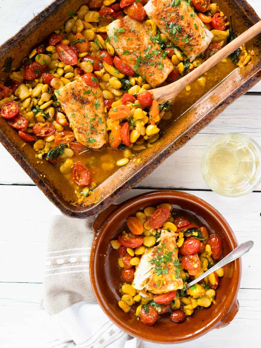 Spanish cod in clay baking dish with one portion on the side.