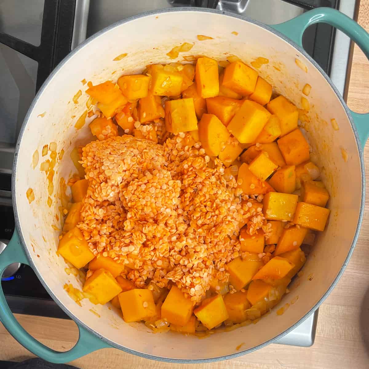 red curry, squash and lentils are added to the pot.