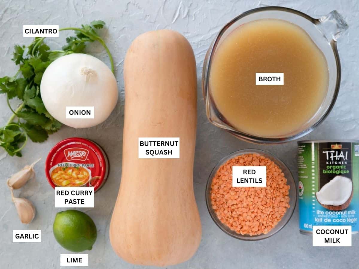 all ingredients needed to make butternut squash and lentil soup labeled and on a board. 