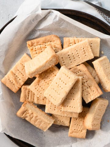 shortbread cookies in a pile on a parchment lined round tray.