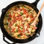 creamy brussels sprouts in a cast iron pan with a wooden serving spoon.