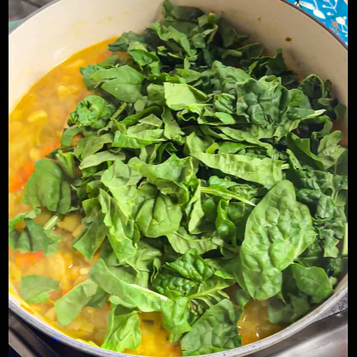 spinach being added to the soup pot. 