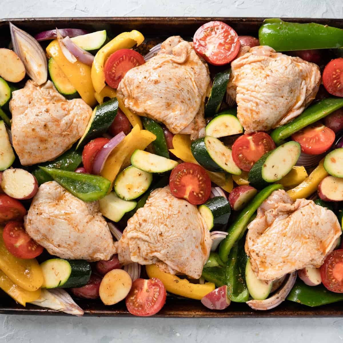 chicken thighs nestled into the vegetables before baking. 