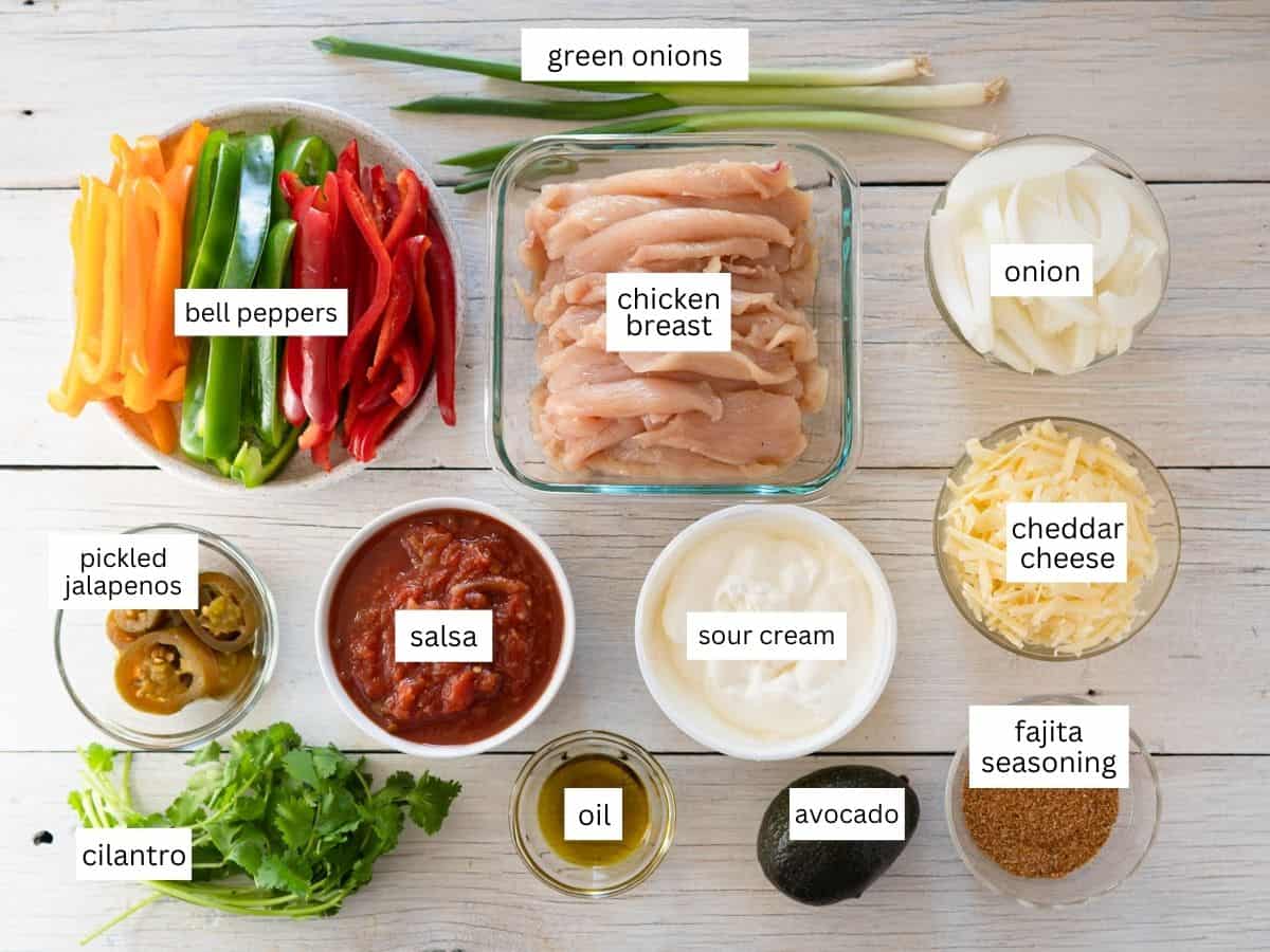 all ingredients to make chicken fajita casserole are labeled and on a white surface. 