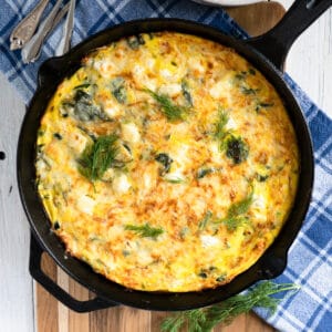 baked frittata in a cast iron skillet after coming out of the oven.