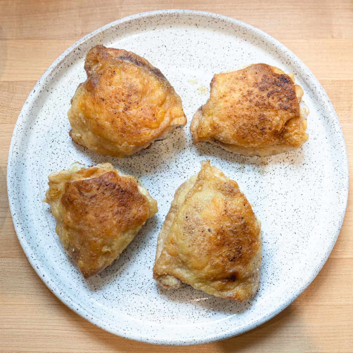 browned chicken thighs on a white plate. 