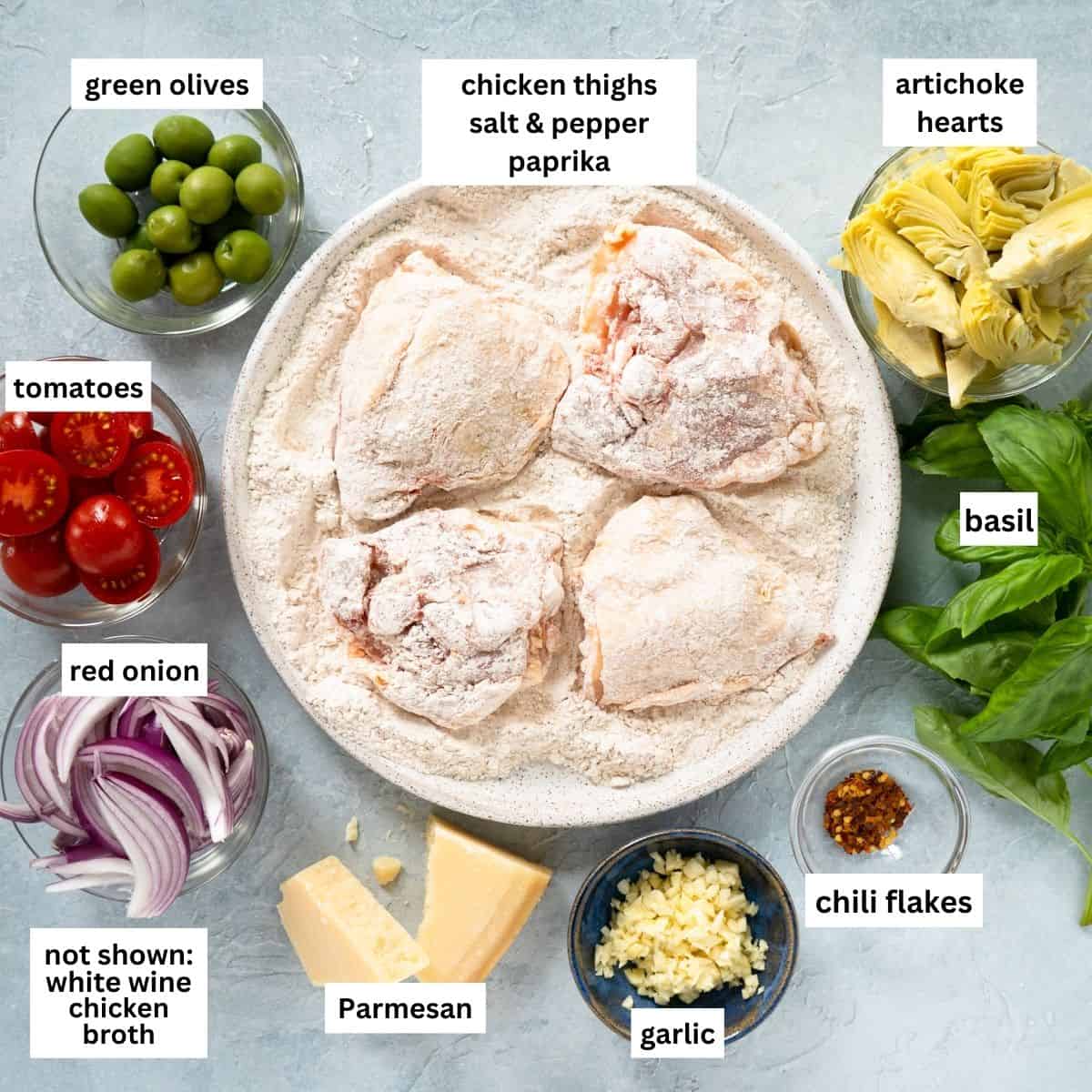 All ingredients needed to make Mediterranean chicken thighs laid out and labeled on a light backdrop.