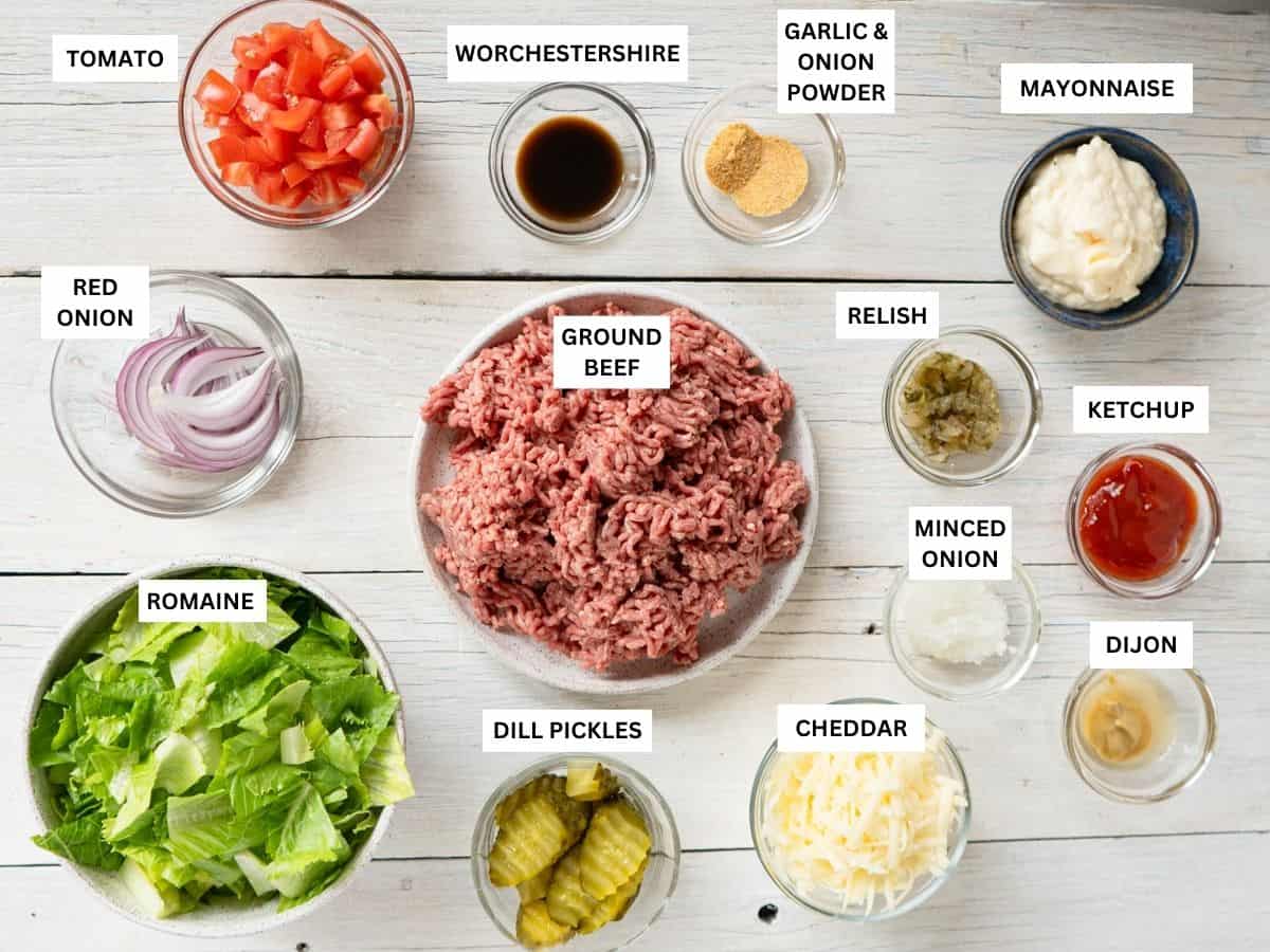 all ingredients needed to make a burger bowl laid out and labeled on a white board.