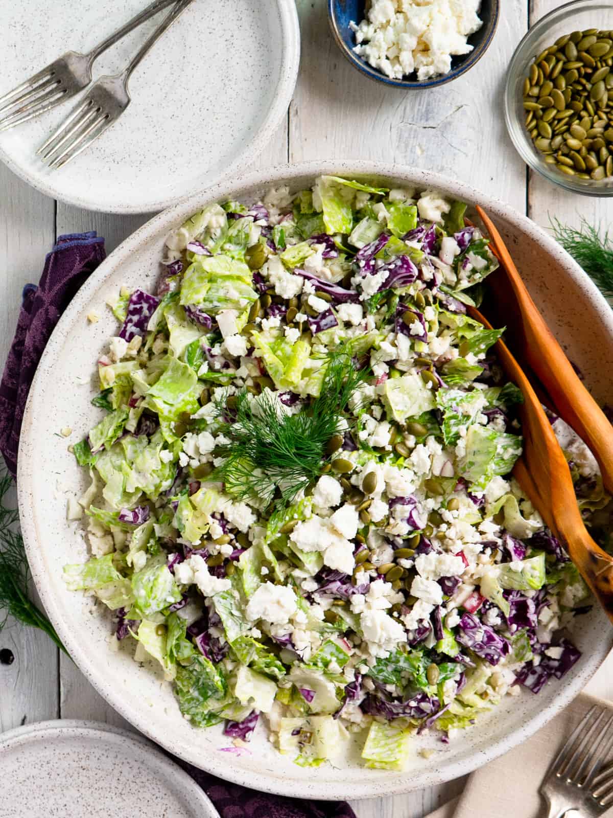 the completed dill pickle salad on a white platter with wooden serving utensils. 