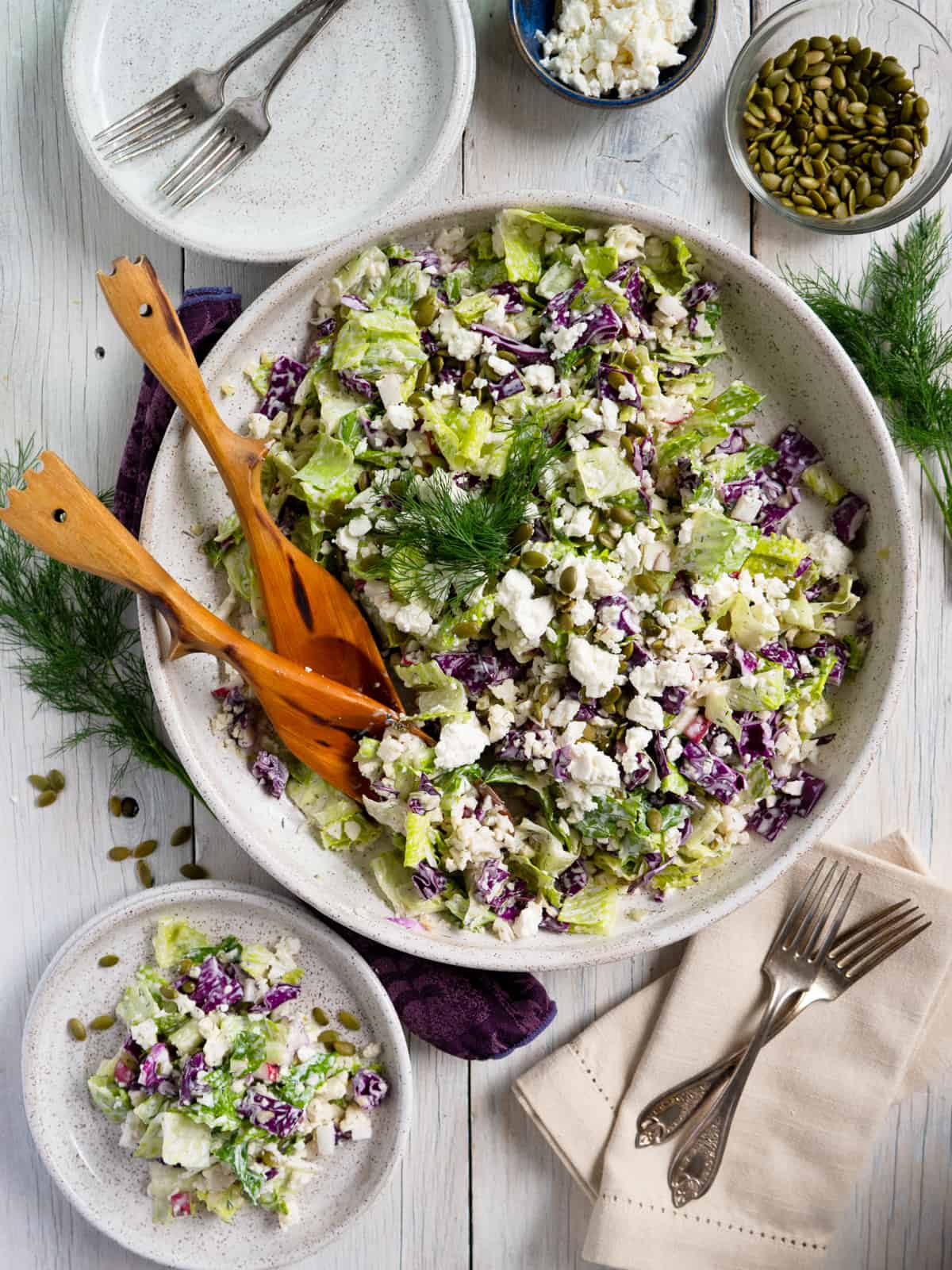 dill pickle salad on a white serving platter with one portion on a small plate to the side. 