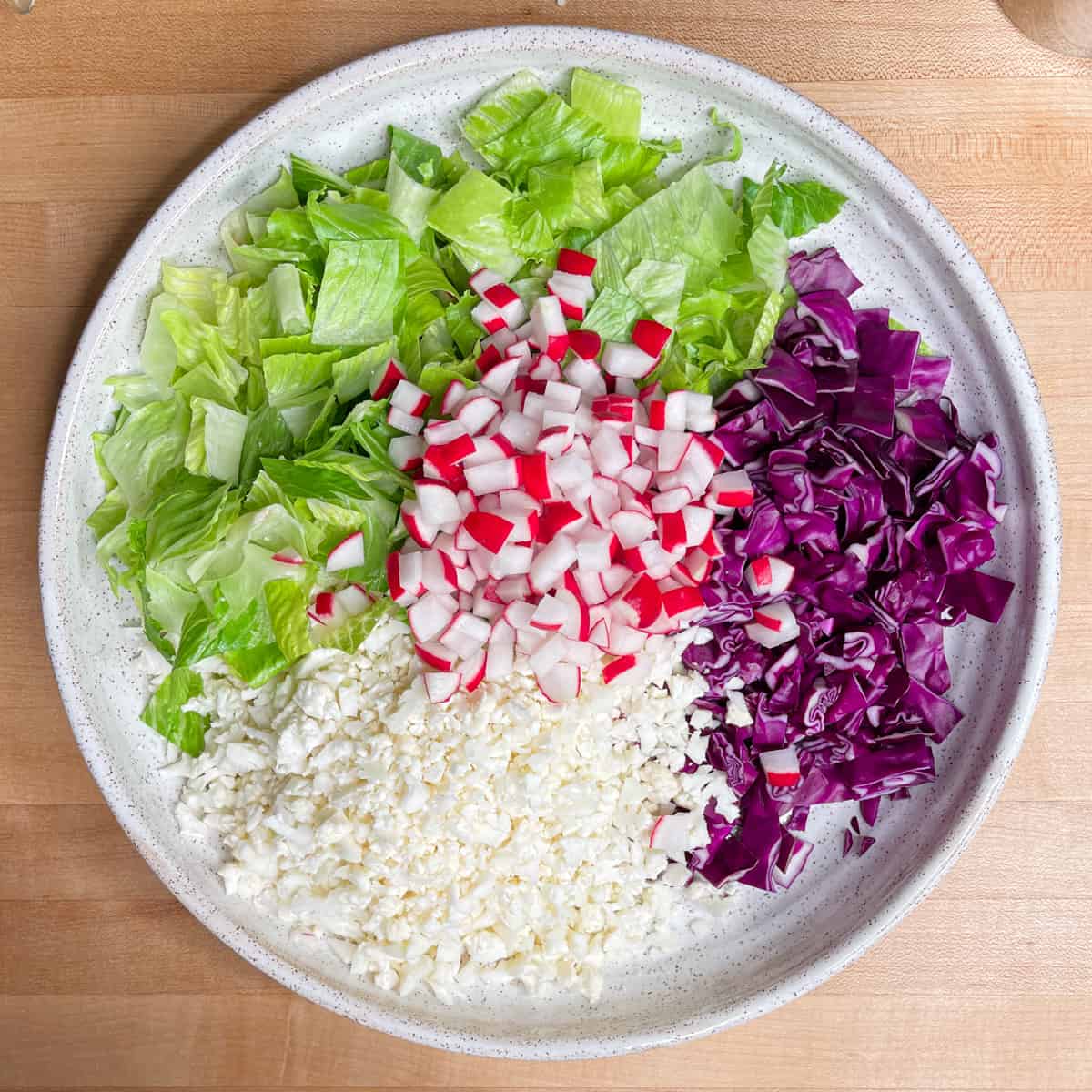 all the prepared vegetables for the salad are laid out on a platter. 