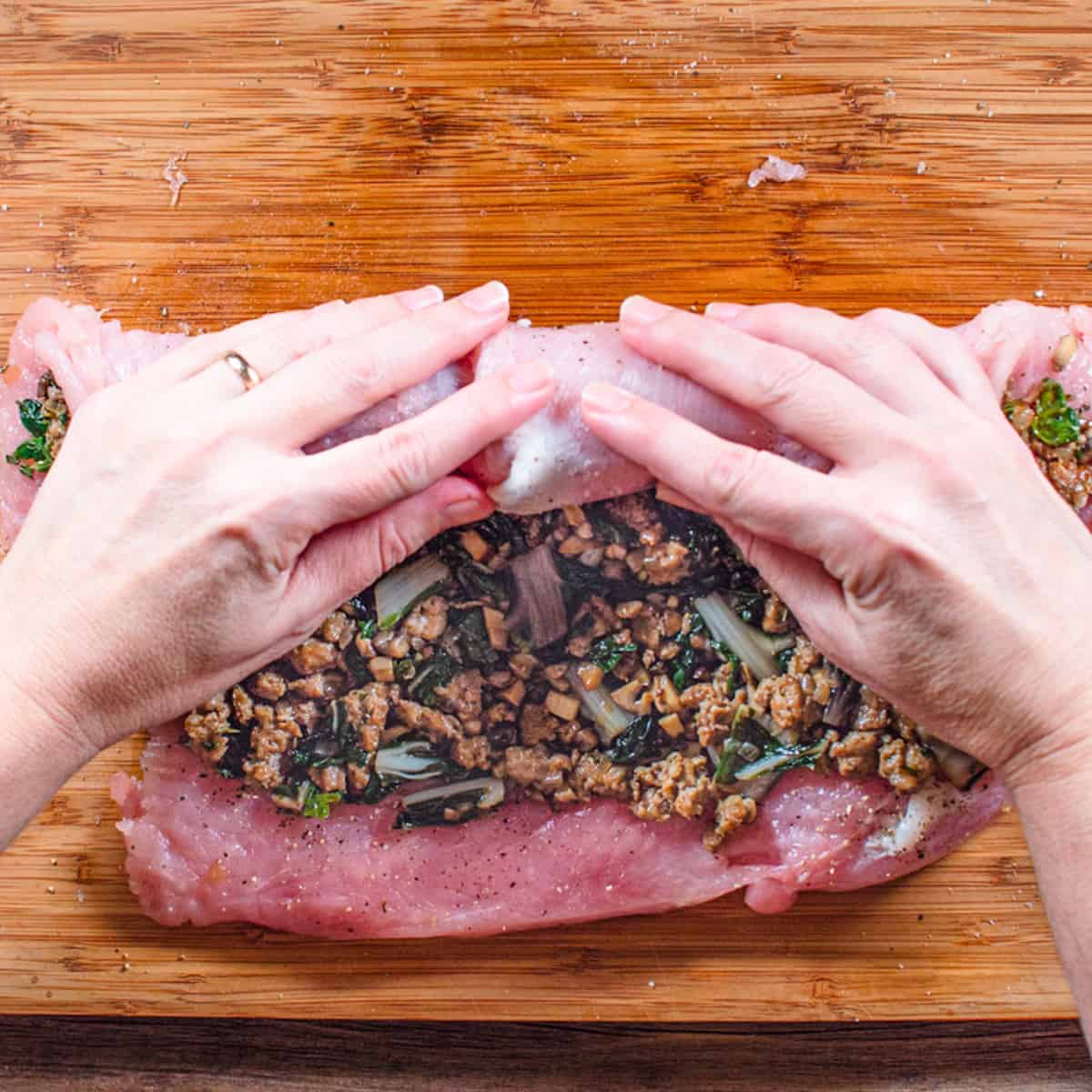 Stuffing is being rolled up in the turkey breast. 