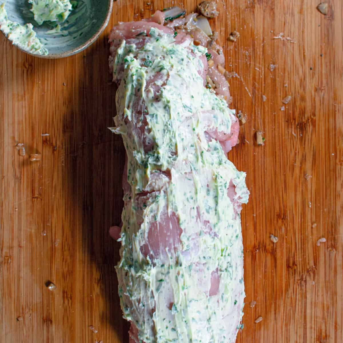 parsley butter is evenly spread over the rolled up turkey breast
