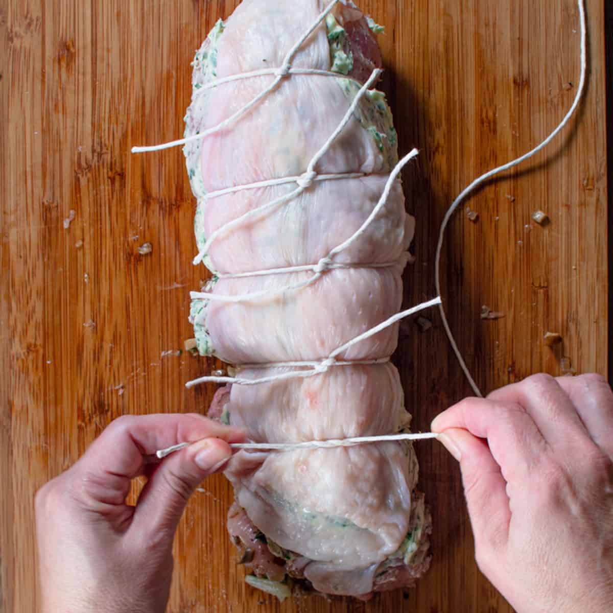 turkey roll being tied up with butcher's twine. 