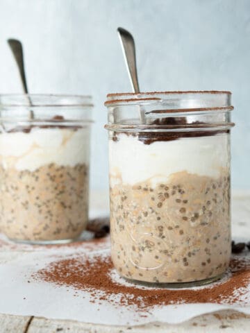 2 jars of tiramisu overnight oats showing the layers and a spoon in each jar.